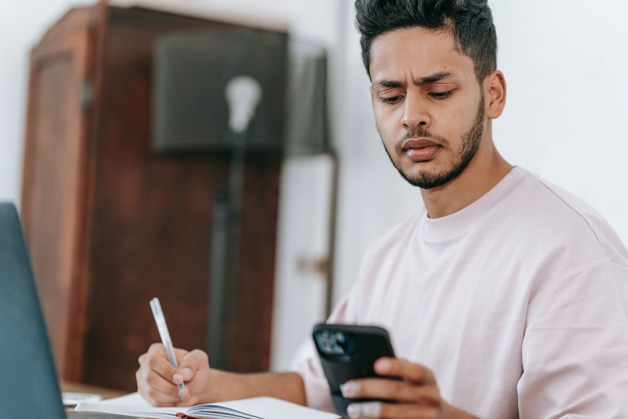 Jovem colaborador estudando com caderno e celular durante treinamento corporativo