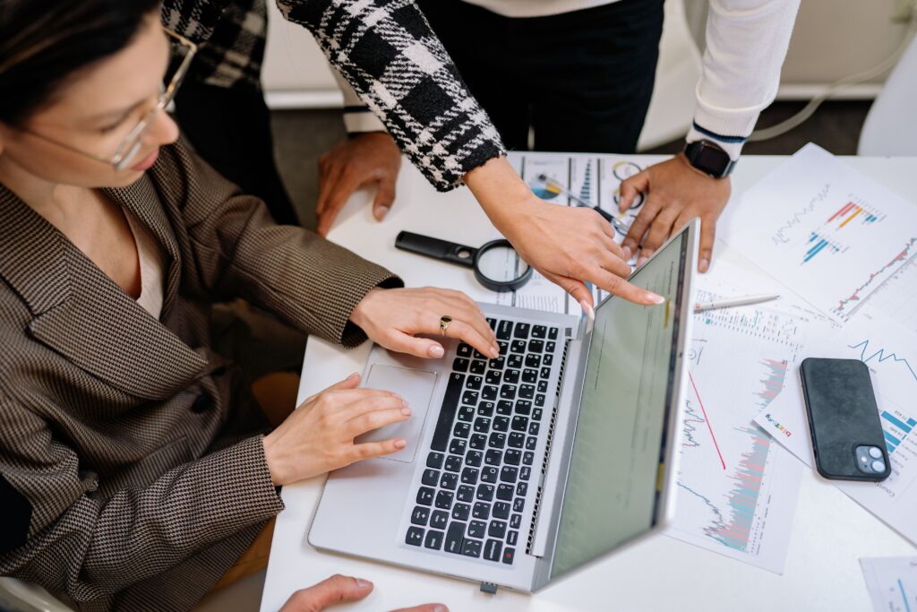 Equipe reunida ao redor de um notebook e relatórios impressos para a atualização de materiais ao novo marco regulatório da EaD