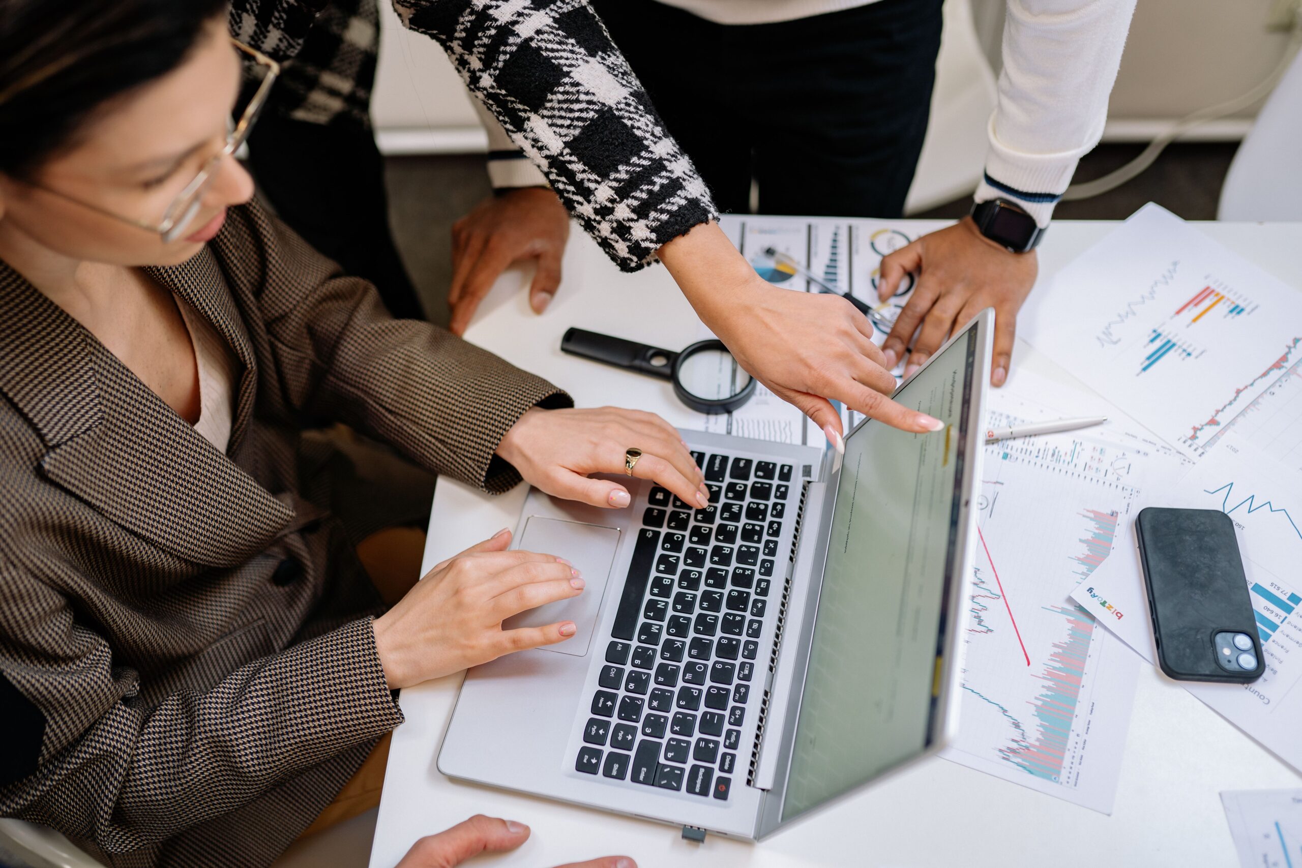 Equipe reunida ao redor de um notebook e relatórios impressos para a atualização de materiais ao novo marco regulatório da EaD