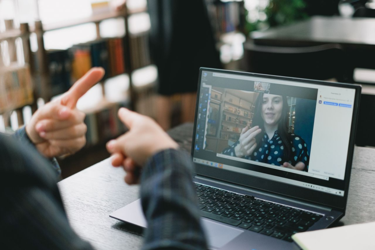 Pessoa conversa em língua de sinais com uma mulher em videochamada no notebook, exemplo de acessibilidade na EaD